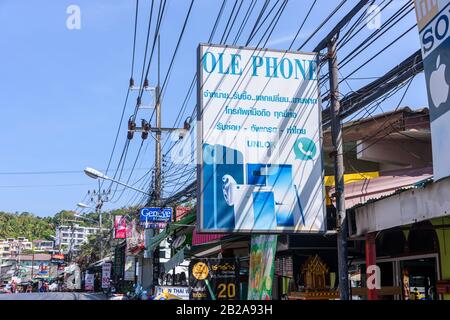 Panneau pour un magasin de réparation de téléphone mobile et de tablette avec des câbles électriques désordonnés et désordonnés accrochés à un poteau d'électricité, Kata, Thaïlande Banque D'Images
