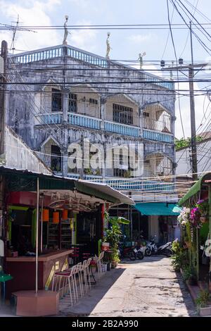 Câbles électriques désordonnés et mal rangés accrochés à un poteau électrique au-dessus d'une rue étroite dans Kata Village, Thaïlande Banque D'Images