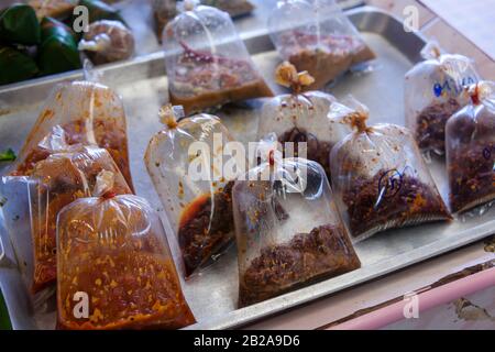 Sacs en plastique remplis de pâtes de cuisine thaïlandaise traditionnelles en vente dans un étalage de marché, Phuket, Thaïlande Banque D'Images