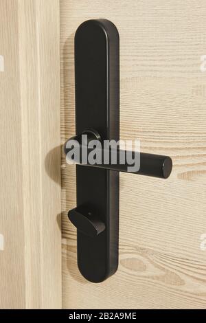 Bouton de porte métallique moderne sur une porte en bois. Chambre d'hôtel Banque D'Images