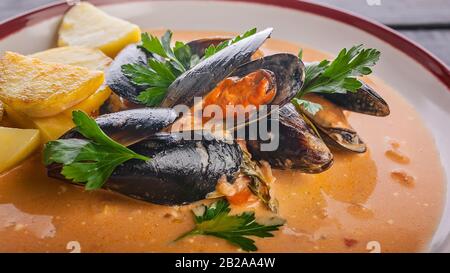 Bannière alimentaire. Moules de gros plan et pommes de terre frites dans une sauce aigre-douce sur une table en bois sombre. Banque D'Images