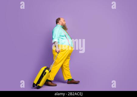 Pleine longueur taille du corps profil vue latérale de son homme funky mûr marchant tenant dans le sac à main de départ compagnie aérienne isolée sur vif vif Banque D'Images