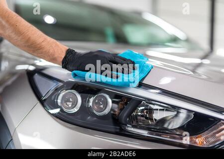 Esthétique auto - l'homme tient la main en microfibre et lustre la voiture. Focus sélectif. Banque D'Images