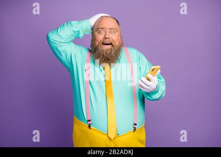 Crazy surprise choqué homme blogger avec grand ventre utilisation smartphone rouge incroyable médias sociaux nouvelles impressionné porter teal rose suspenders pantalon Banque D'Images