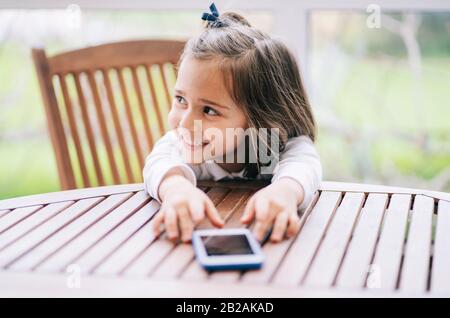 Une petite fille utilise un smartphone de téléphone mobile à la maison Banque D'Images