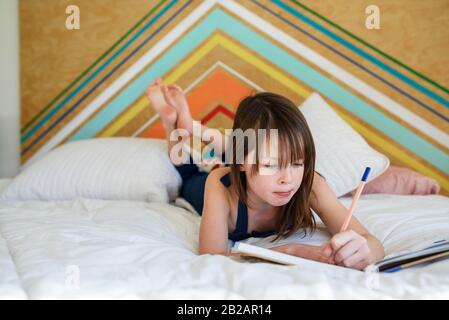 Portrait d'une fille posée sur son lit faisant ses devoirs Banque D'Images