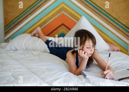 Portrait d'une fille posée sur son lit faisant ses devoirs Banque D'Images