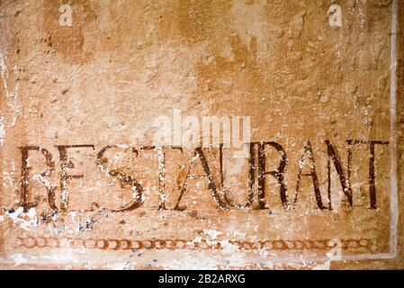 Vieux mur de plâtre texturé et résisté à l'weathered avec texte « restaurant » sur lui Banque D'Images