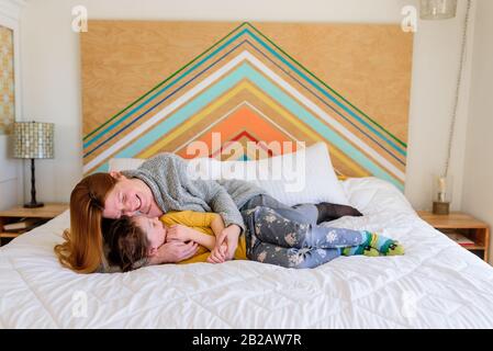 Mère et fille posée sur un lit couddling Banque D'Images