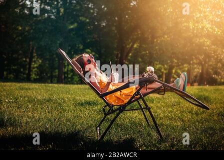 Bonne fille assise dans le jardin avec un poulet sur ses genoux Banque D'Images