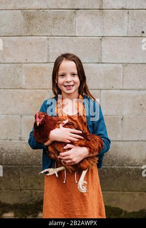 Portrait d'une fille souriante tenant un poulet, États-Unis Banque D'Images