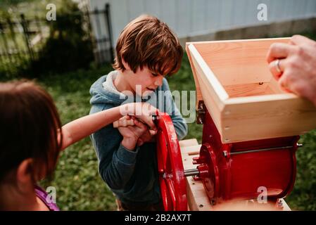 Deux enfants aidant leur père à presser des pommes pour faire du cidre, États-Unis Banque D'Images