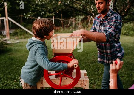 Deux enfants aidant leur père à presser des pommes pour faire du cidre, États-Unis Banque D'Images