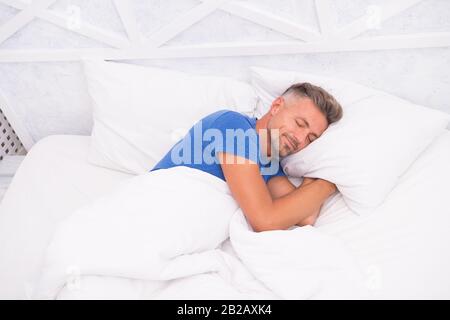 Homme mûr et calme, reposant. Bon Sommeil Est Accessible Dream. Journée Mondiale Du Sommeil. Avantages d'un bon sommeil et d'un sommeil sain. Respirez Facilement, Dormez Bien. Bel homme au lit. Un gars qui dormait à la maison. Besoin de repos. Banque D'Images