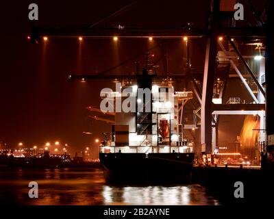 Conteneurs les navires chargés et déchargés la nuit sous une grande lune au Port de Felixstowe. Banque D'Images