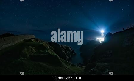 Poutres lumineuses du phare de Fanad Head dans la nuit sombre avec ciel plein d'étoiles. Photographie en exposition longue. Wild Atlantic Way, Donegal, Irlande Banque D'Images