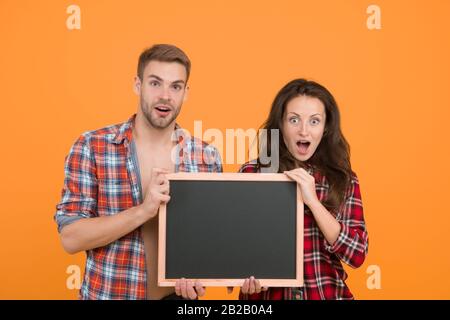 Couple avec tableau noir pour la publicité. Surpris couple jaune fond. Homme et femme publicité produits. Informations sur les réductions. Vente finale. C'est une grande surprise. Vraiment bonne nouvelle. Banque D'Images