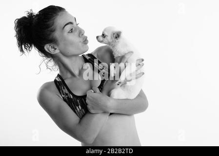 Portrait of teenage girl holding tout en embrassant mignon chien prêt pour le sport et l'exercice contre fond blanc Banque D'Images