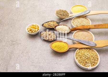 Concept de nourriture saine végétarienne (végétalien). Assortiment de céréales biologiques, légumineuses, grains entiers. Dans des bols en céramique et des cuillères en bois sur un backgr en pierre Banque D'Images