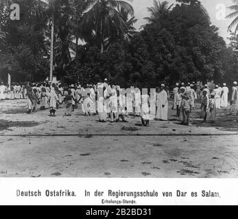 Cours de relaxation à l'école publique de Dar es Salaam en Afrique de l'est allemande. Les enfants peuvent être vus sur le terrain de jeu dans des vêtements typiques d'Afrique noire, d'arabe et d'Europe. Banque D'Images