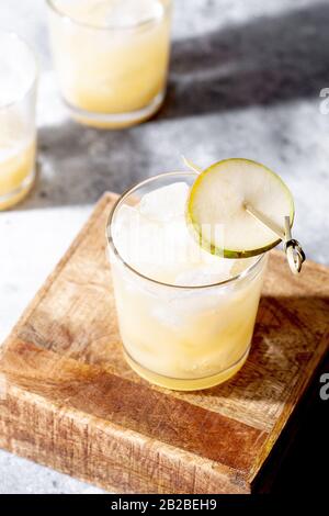 Cocktail de poire froide ou queue de bœuf avec purée de soda et de poire et tranches de fruits en verre court sur fond gris avec gros plan. Un été rafraîchissant Banque D'Images