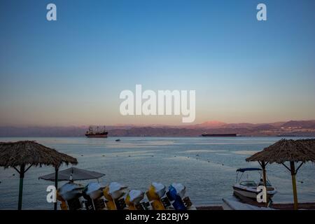 Aqaba, JORDANIE - 31 JANVIER 2020: Très tôt le matin mais les bateaux touristiques attendent des touristes curieux, la plage de la ville. Hiver ciel de vacances clair autour du lever du soleil. golfe de la Mer Rouge, Royaume hachémite de Jordanie Banque D'Images