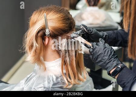 Coiffure en noir gants est une teinture de cheveux de femme. Coiffure est d'une couleur crème à cheveux. La peinture sèche. Banque D'Images