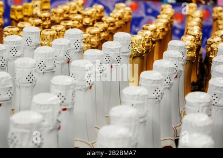 Grande quantité de bouteilles de champagne dorées et blanches necks et casquettes supérieures sur fond clair Banque D'Images