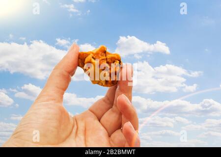 Orange dans la main avec une réflexion vive sur la paume contre le fond de la mer. Lumière vive de la pierre solaire dans la main femelle. Minéral de RE Banque D'Images