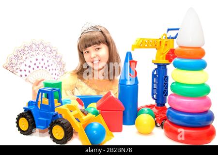 Jeune fille dans une belle robe et des jouets de couleur vive sur un fond blanc isolé. Banque D'Images