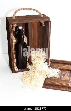 Une bouteille de vin rouge dans une boîte en bois, des copeaux de bois sur le fond. Isolé sur fond blanc Banque D'Images