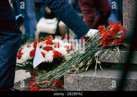 En posant des fleurs au monument, un soldat en gants blancs met des fleurs au monument des soldats morts dans la seconde guerre mondiale Banque D'Images