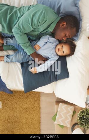 Portrait de l'homme afro-américain adulte dormant avec son petit-fils tout en allongé sur le lit à la maison, espace de copie Banque D'Images