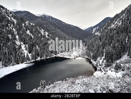 Vue aérienne sur le lac de montagne de Kolsay et la forêt enneigée en hiver dans les montagnes du Kazkakhstan. Banque D'Images