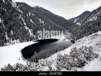 Vue aérienne sur le lac de montagne de Kolsay et la forêt enneigée en hiver dans les montagnes du Kazkakhstan. Banque D'Images