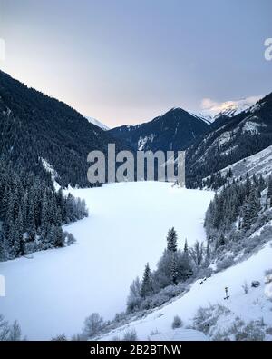 Paysage du lac de montagne de Kolsay et forêt enneigée au lever du soleil en hiver dans les montagnes du Kazakhstan. Banque D'Images