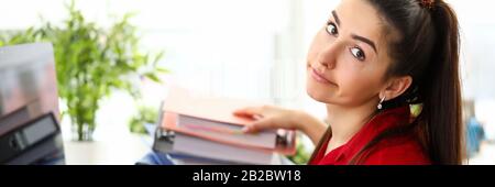 Jeune femme assise au bureau avec un tas de documents et se sentant stressée Banque D'Images