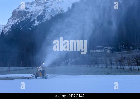 Machine à neige déversant de la neige artificielle sur une piste de ski à Engelberg sur les alpes suisses Banque D'Images