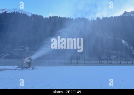 Machine à neige déversant de la neige artificielle sur une piste de ski à Engelberg sur les alpes suisses Banque D'Images