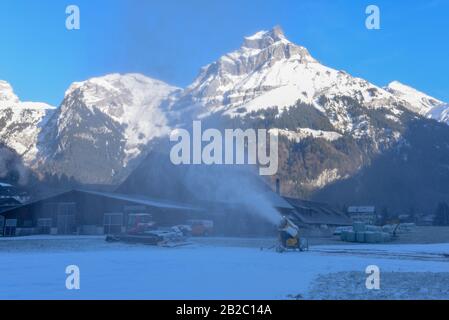 Machine à neige déversant de la neige artificielle sur une piste de ski à Engelberg sur les alpes suisses Banque D'Images