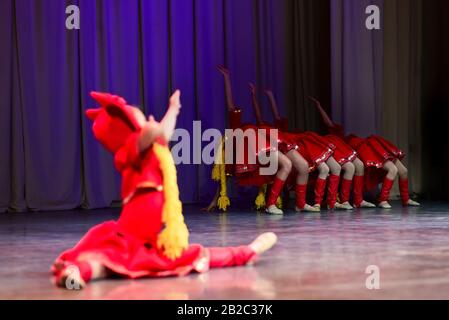 Les jeunes filles en robes rouges dansent les danses folkloriques russes sur scène. Banque D'Images