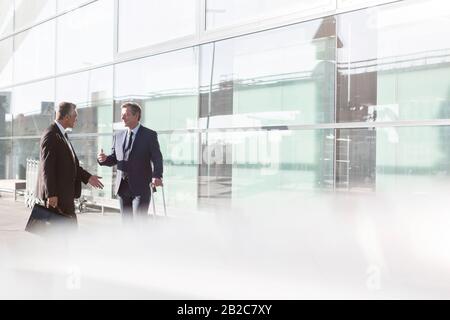 Hommes d'affaires discutant de plans à l'aéroport Banque D'Images