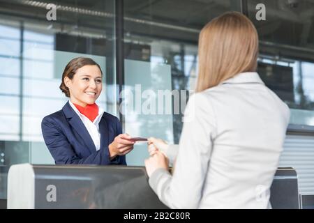 Jeune agent attirant du service passagers donnant passeport et carte d'embarquement de femme d'affaires après l'enregistrement Banque D'Images