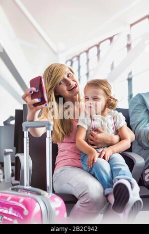 Portrait de la jeune adolescente prenant selfie avec sa petite sœur en attendant l'embarquement à l'aéroport Banque D'Images