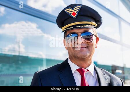 Portrait d'un capitaine de pilote expérimenté et confiant portant des lunettes à l'aéroport Banque D'Images