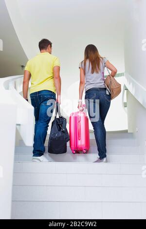 Vue arrière de jeunes couples marchant à l'étage pour s'enregistrer dans leur chambre à l'hôtel Banque D'Images