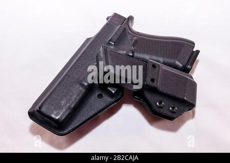 Pistolet noir dans un étui en plastique avec un étui de magasin chargé sur fond blanc Banque D'Images