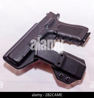 Pistolet noir dans un étui en plastique avec un étui de magasin chargé sur fond blanc Banque D'Images