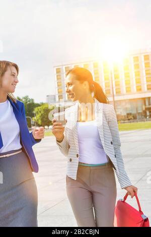 Les femmes d'affaires qui tiennent une tasse de café tout en parlant sur la route Banque D'Images