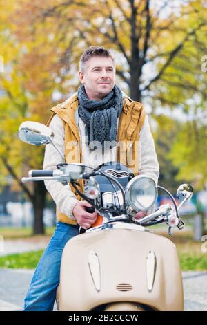 Portrait d'un homme mûr et séduisant assis sur un vélo tout en attendant dans le parc Banque D'Images